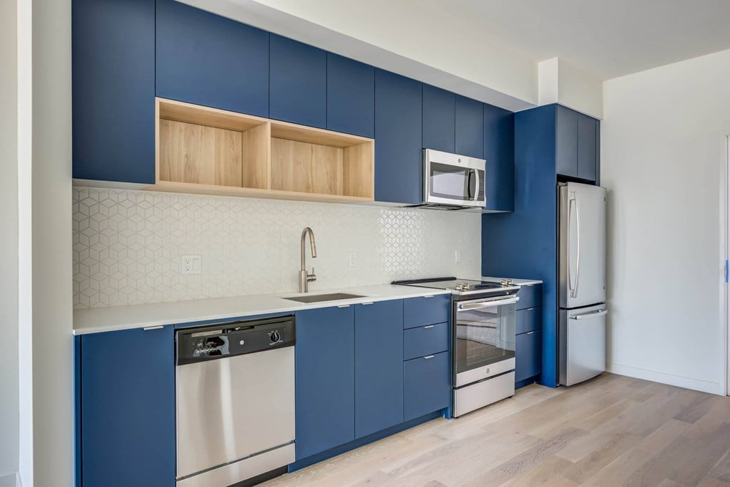 A kitchen with blue cabinets and a white backsplash.at Junction 4121, Los Angeles, 90029