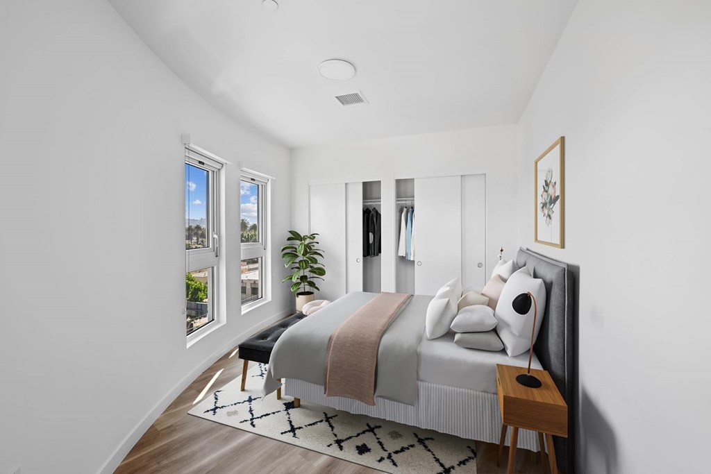 A bedroom with a large bed and a window overlooking a cityscape.