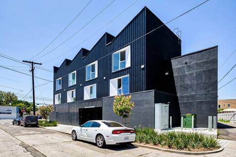 A modern black building with a white car parked in front.