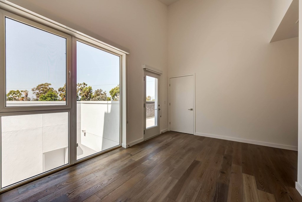 A room with a wooden floor and a view of trees through the window.at 5263 W Adams, California