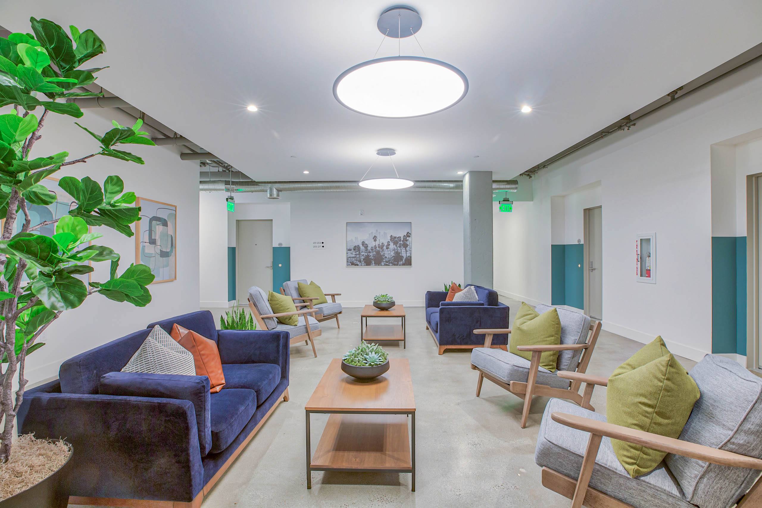 A living room with blue couches and wooden chairs.