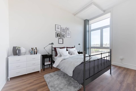 A bedroom with a black metal bed and a white dresser.