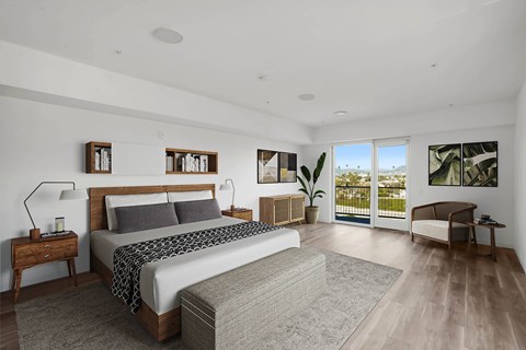 A bedroom with a large bed and a view of the outdoors through a sliding glass door.