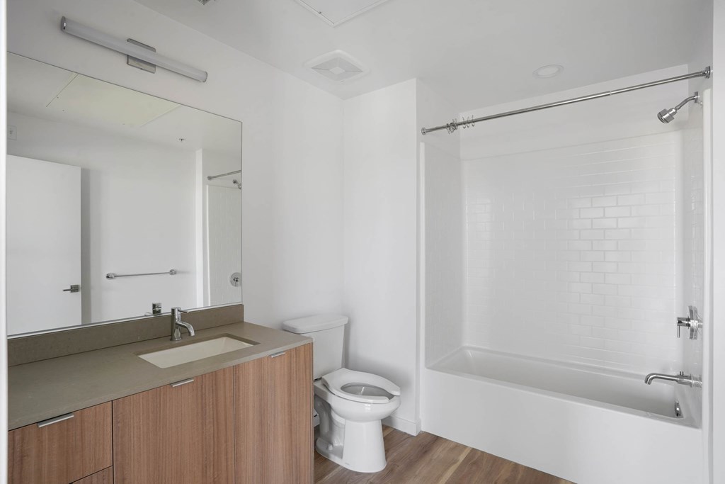 A white bathroom with a toilet, sink, and shower.at 2221 S Western, California, 90018