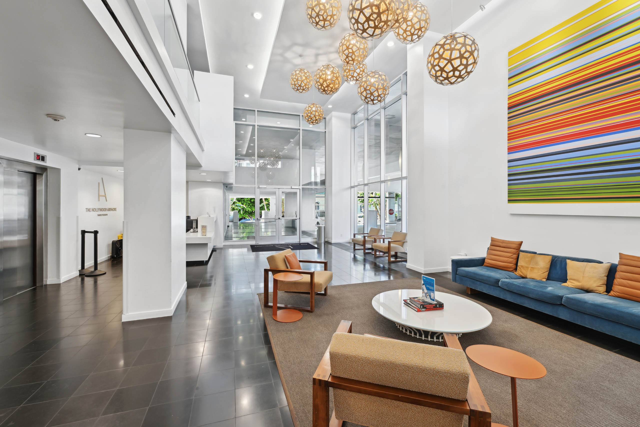 A modern living room with a blue couch and a colorful painting on the wall.