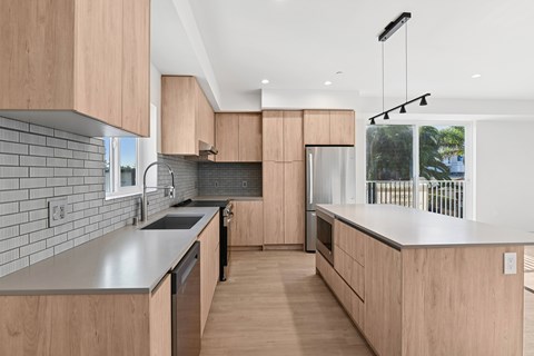 A modern kitchen with wooden cabinets and a grey countertop.