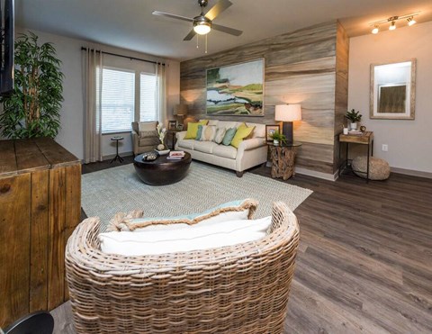 A living room with a wicker sofa and a painting on the wall.