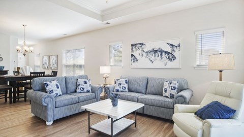 A living room with a grey couch, a white armchair, and a coffee table at Stepping Stone at Bridgewater Apartments, Little River, South Carolina