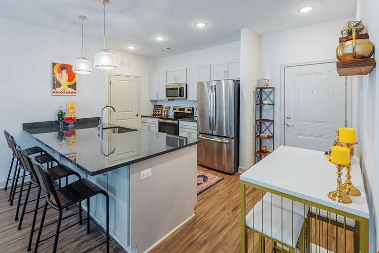 A kitchen with a black countertop and stainless steel appliances.at Riverside Flats at Aberfoyle Village, North Carolina, 28012