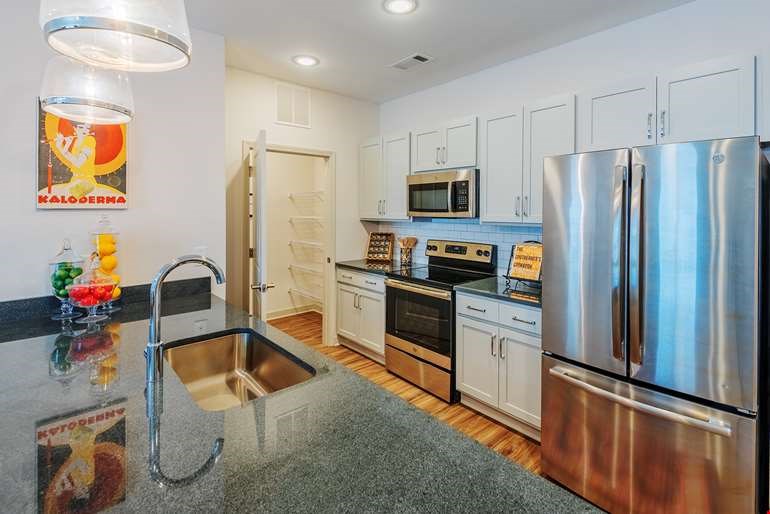 A kitchen with a stainless steel refrigerator and a sink with a faucet.at Riverside Flats at Aberfoyle Village, North Carolina
