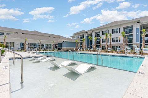 A large swimming pool in front of a building with palm trees. at The Banks at Bridgewater Apartments, South Carolina, 29566