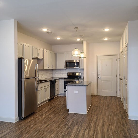 A kitchen with a refrigerator, microwave, oven, and cabinets.at Riverside Flats at Aberfoyle Village, Belmont, 28012