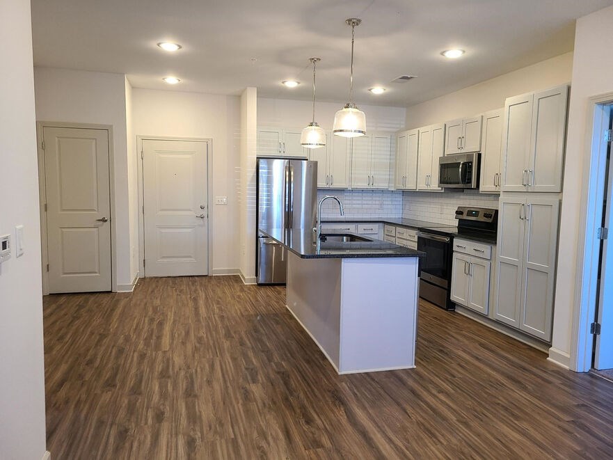 A kitchen with a white island and wooden floors.at Riverside Flats at Aberfoyle Village, Belmont, NC