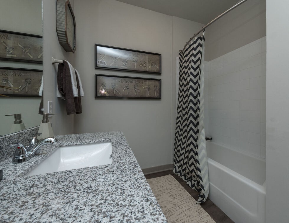 A bathroom with a granite counter top and a shower with a black and white curtain. at Mariner Grove, Savannah, Georgia