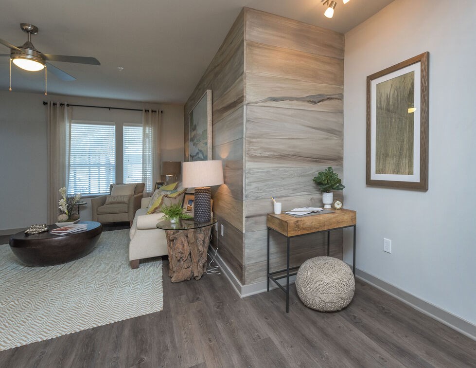 A living room with a wooden accent wall and a ceiling fan. at Mariner Grove, Savannah, GA