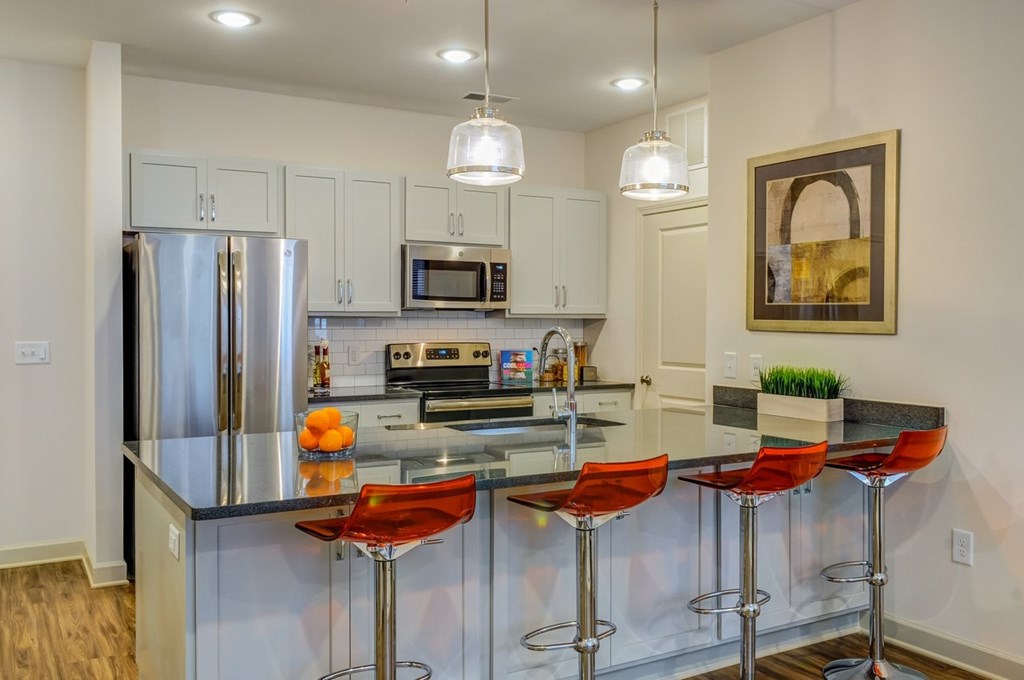 A modern kitchen with a bar area and stools.at Riverside Flats at Aberfoyle Village, Belmont, NC 28012
