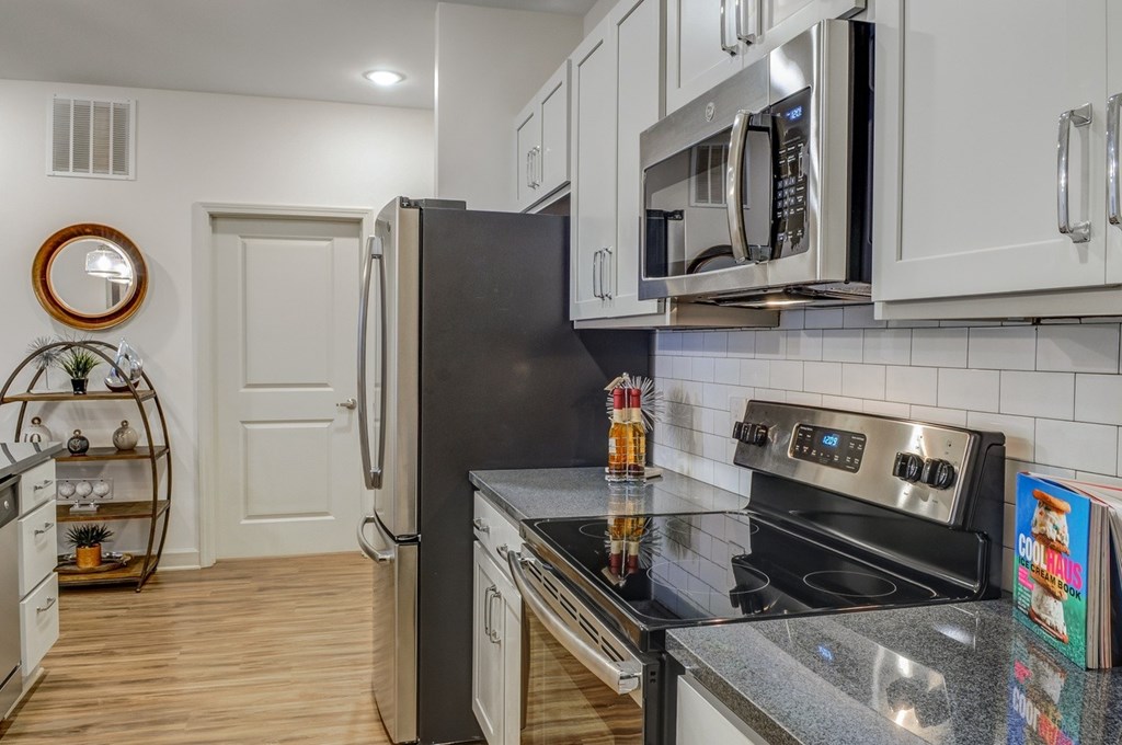 A modern kitchen with a black refrigerator and stove top oven.at Riverside Flats at Aberfoyle Village, North Carolina, 28012