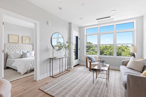 A bedroom with a large bed and a window overlooking a tree-filled landscape.