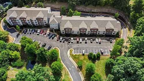 An aerial view of a parking lot with cars and a building with a grey roof.