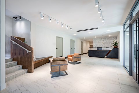 A modern interior space with a staircase, seating area, and glass doors.