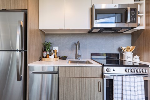 A modern kitchen with a stainless steel refrigerator, a microwave above the stove, and a sink with a faucet.