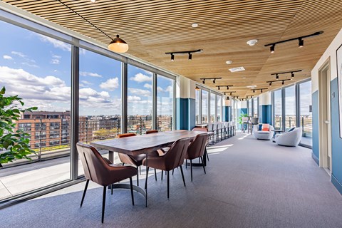 A conference room with a long table and chairs with a view of the city outside the window.