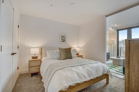 A bedroom with a large bed and a nightstand with a lamp.