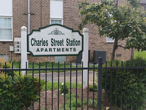 A sign for Charles Street Station Apartments stands in front of a brick building.