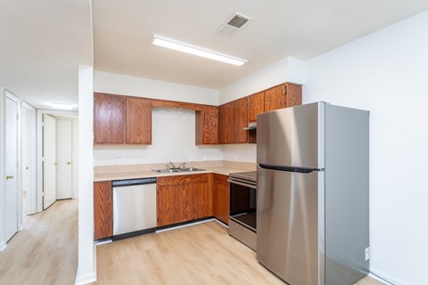 A kitchen with a refrigerator, sink, and cabinets.