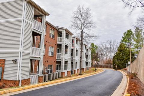 A row of apartment buildings with a road in front.