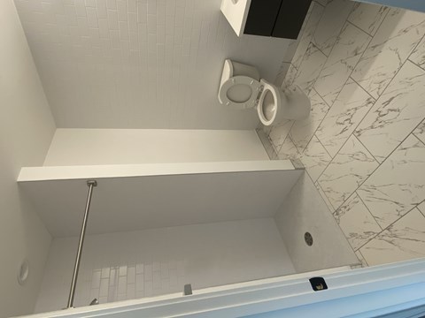 A white toilet is mounted on a white tiled wall.