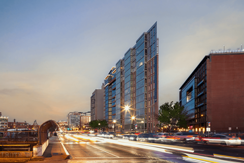 A long exposure shot of a city street at dusk with a modern building in the background.