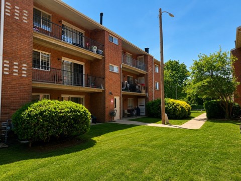 A red brick apartment building with green bushes in front.