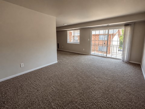A room with carpeted floor and a window with a view of a building.