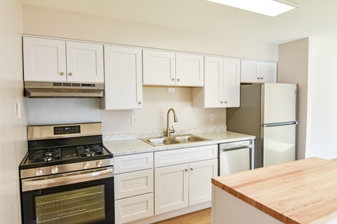A kitchen with white cabinets and a wooden counter top.
