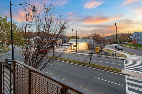 A view of a street from a balcony with a building in the background.