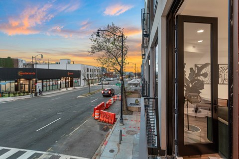 A street view with a building on the right and a car driving on the road.