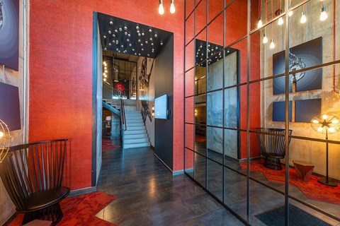 A hallway with a red wall and a black chair.
