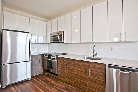A kitchen with a stainless steel refrigerator, microwave, oven, and sink.