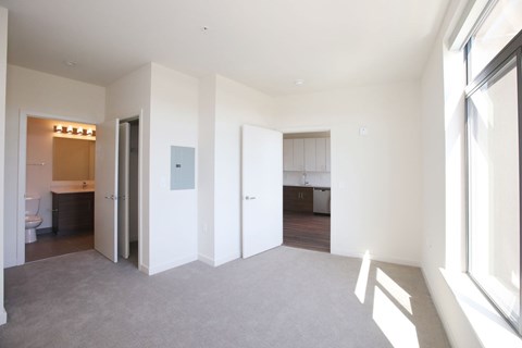 A spacious, empty room with a carpeted floor and white walls.