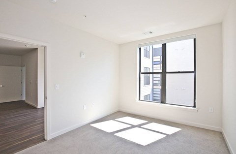 A room with a large window and a view of a building outside.