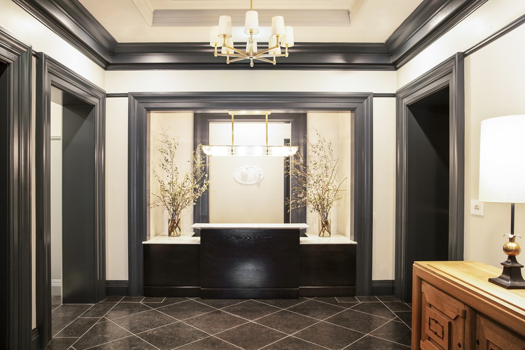 A black and white hallway with a chandelier and a plant.