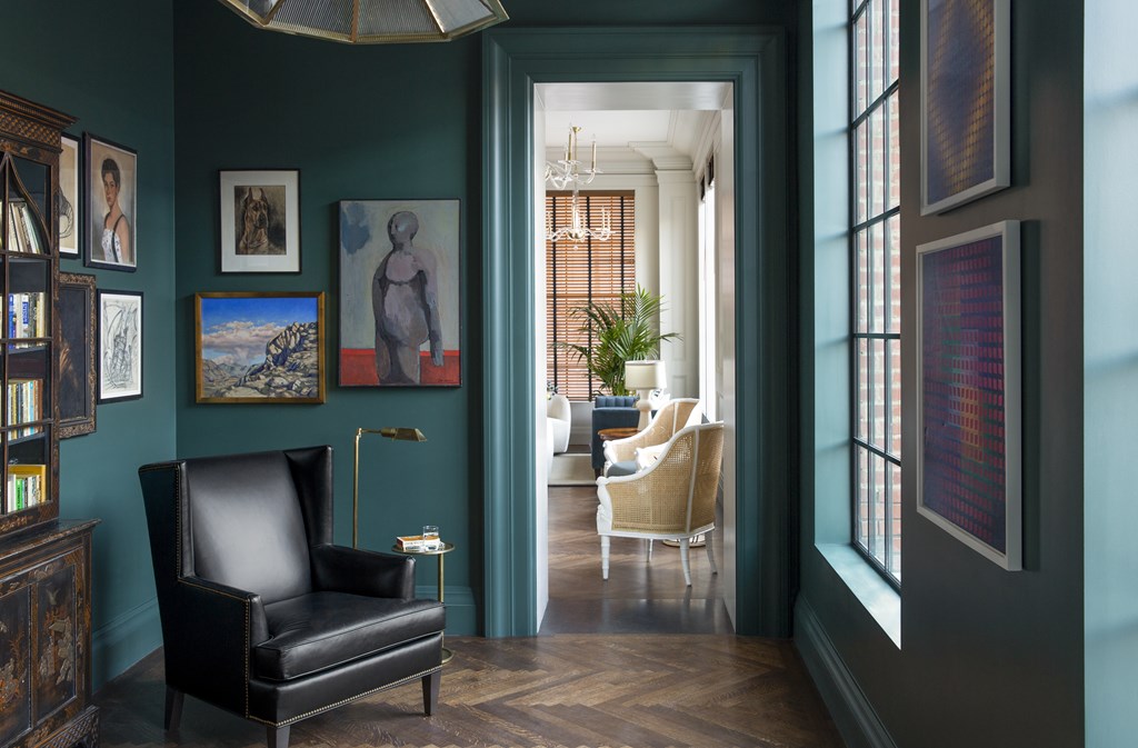 A black leather chair sits in a room with green walls and a wooden floor.