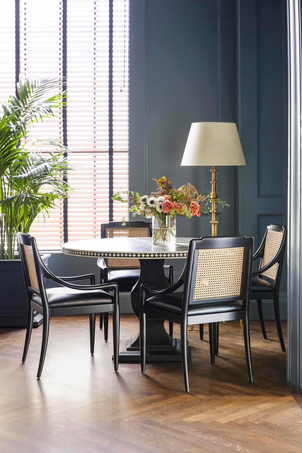 A table with chairs and a lamp in front of a window.