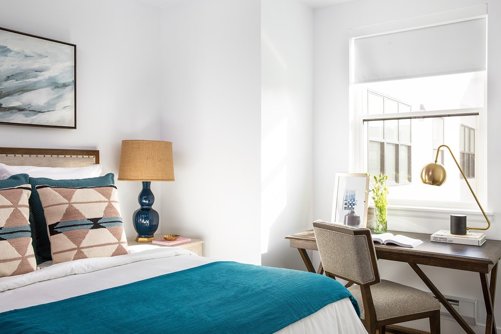 A bedroom with a bed, desk, and chair.