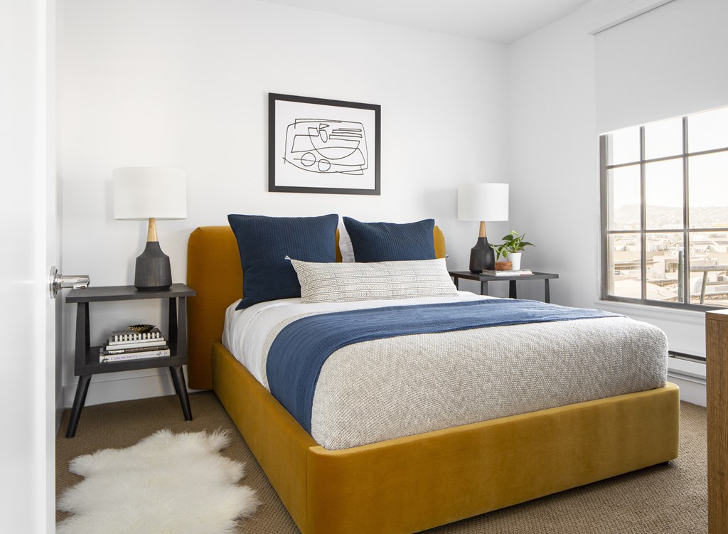 A bedroom with a large bed and a framed picture on the wall.