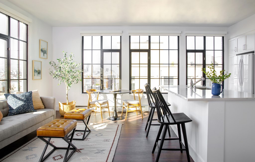 A living room with a white couch, a wooden bench, and a dining table with chairs.
