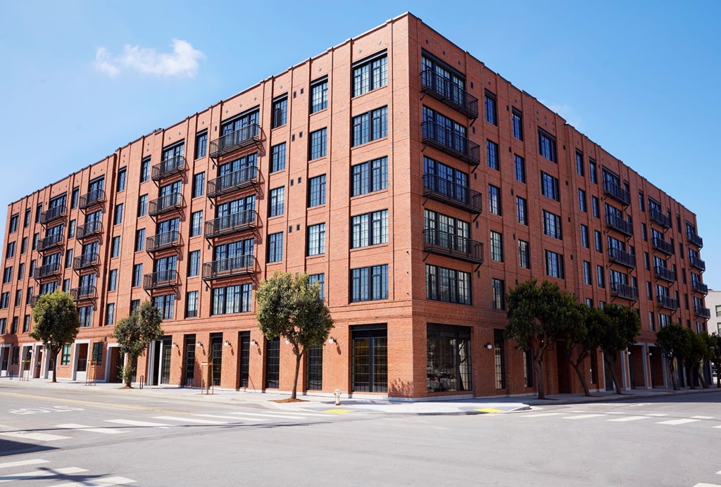 A red brick building with many windows and trees in front.