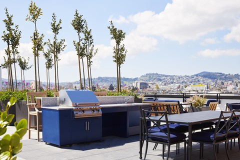 A blue outdoor kitchen with a grill and a table with chairs.
