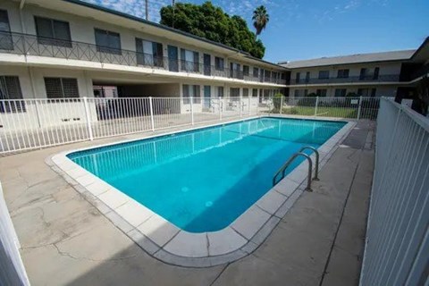 A swimming pool in a courtyard surrounded by a white fence.